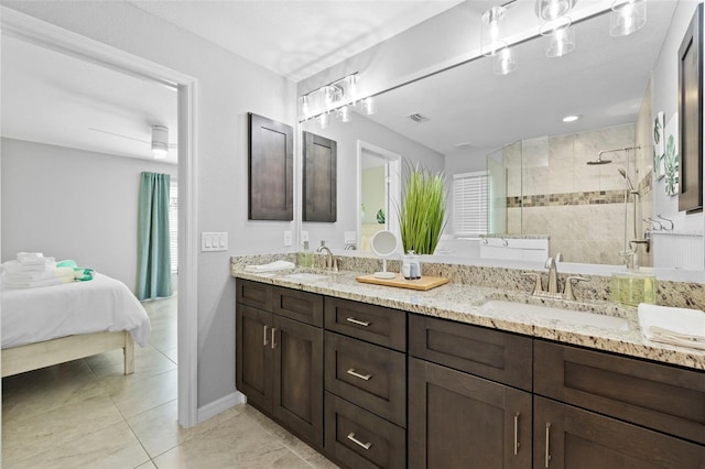 bathroom featuring tile patterned flooring, a tile shower, and vanity