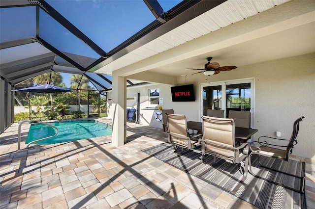 view of swimming pool with a patio, glass enclosure, and ceiling fan