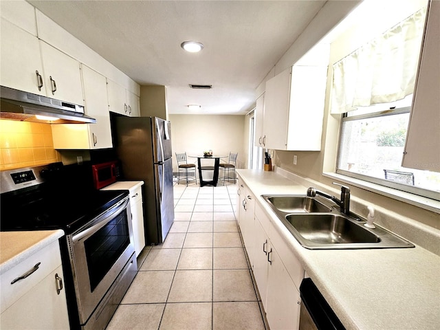 kitchen with light tile patterned flooring, stainless steel appliances, white cabinetry, decorative backsplash, and sink