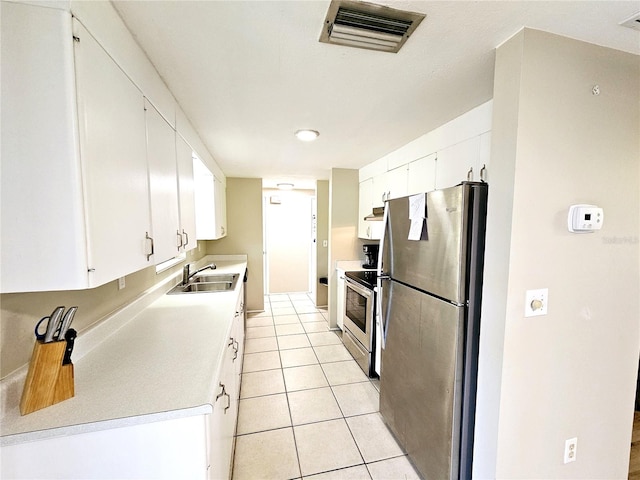 kitchen with white cabinets, stainless steel appliances, sink, and light tile patterned flooring