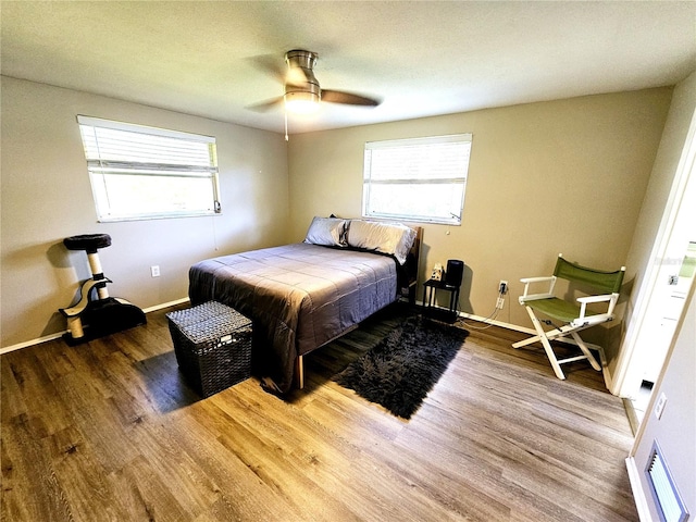 bedroom featuring hardwood / wood-style flooring, ceiling fan, and multiple windows