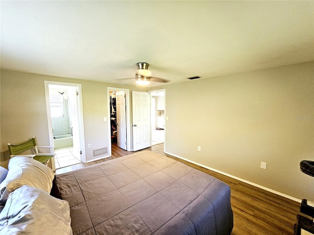 bedroom with light hardwood / wood-style floors, ceiling fan, a walk in closet, connected bathroom, and a closet