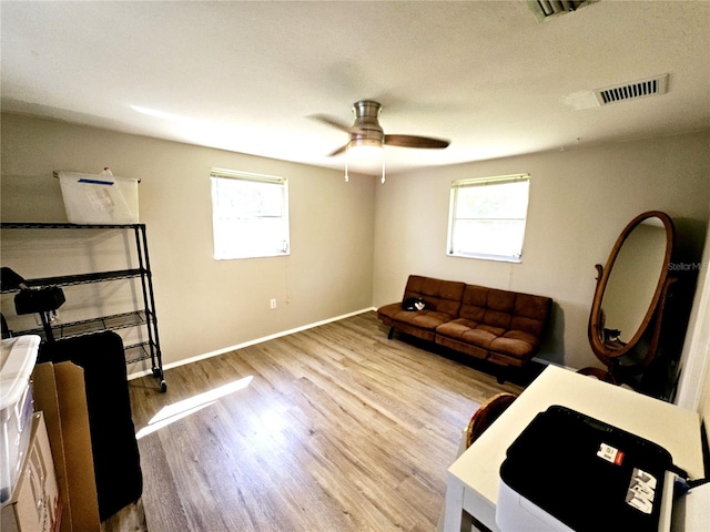 living room with light hardwood / wood-style floors, ceiling fan, and a healthy amount of sunlight