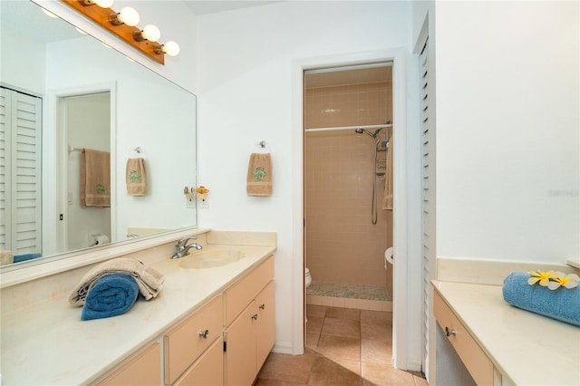 bathroom featuring toilet, tiled shower, tile patterned floors, and vanity