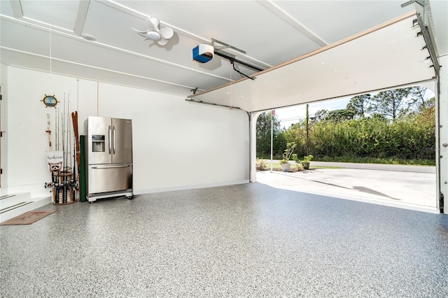 garage with a garage door opener and stainless steel fridge with ice dispenser