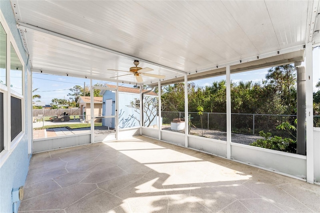 unfurnished sunroom featuring ceiling fan and a healthy amount of sunlight
