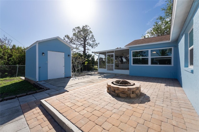 view of patio / terrace featuring a sunroom, a storage shed, and an outdoor fire pit