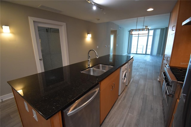 kitchen featuring a kitchen island with sink, sink, pendant lighting, dishwasher, and washer / clothes dryer