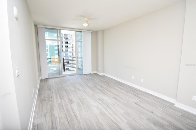 unfurnished room with light hardwood / wood-style flooring, a wall of windows, and ceiling fan