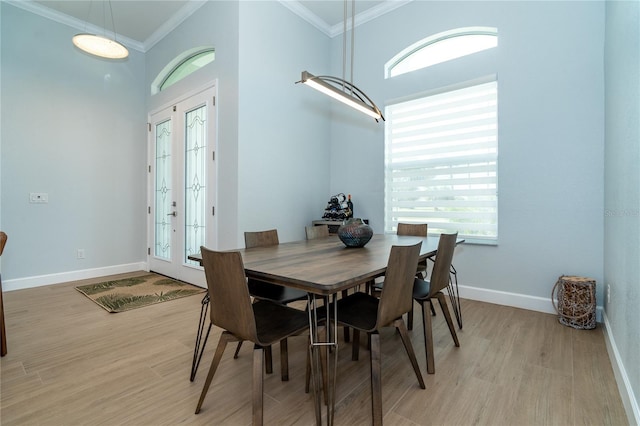 dining room featuring french doors, a towering ceiling, ornamental molding, and light hardwood / wood-style flooring