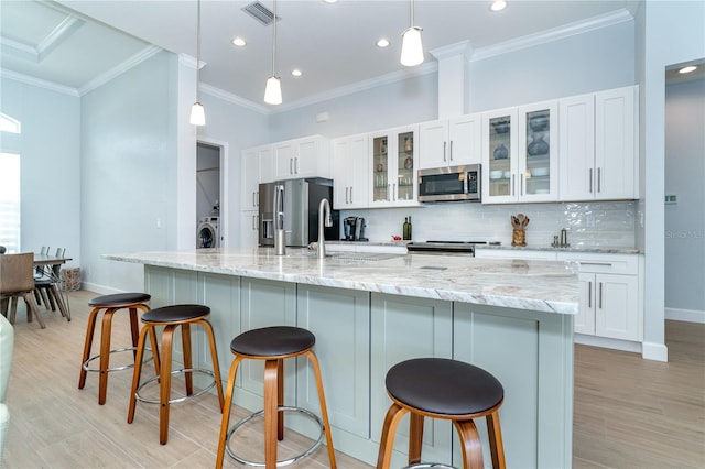 kitchen with hanging light fixtures, white cabinets, a spacious island, and appliances with stainless steel finishes