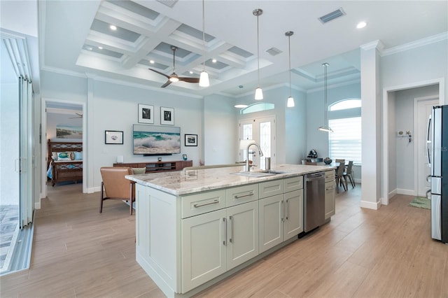 kitchen with appliances with stainless steel finishes, pendant lighting, sink, a kitchen island with sink, and light stone countertops