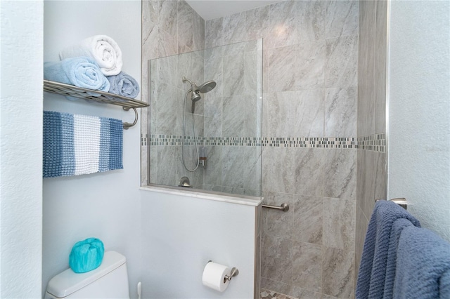 bathroom featuring tiled shower and toilet