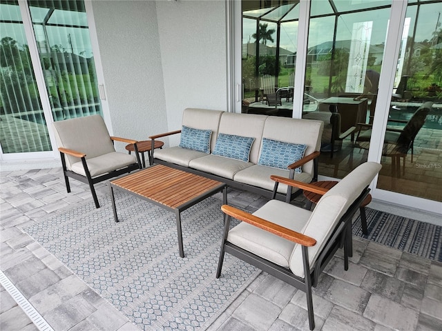 view of patio with an outdoor hangout area and glass enclosure