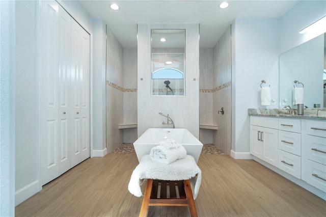 bathroom featuring hardwood / wood-style flooring, vanity, independent shower and bath, and tile walls