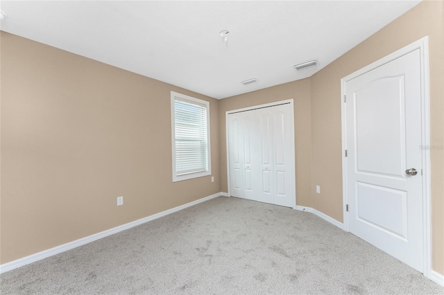 unfurnished bedroom with a closet and light colored carpet