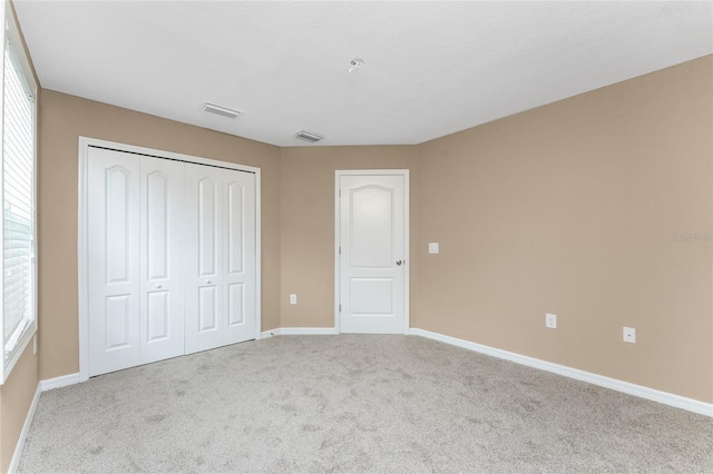 unfurnished bedroom with light carpet and a closet