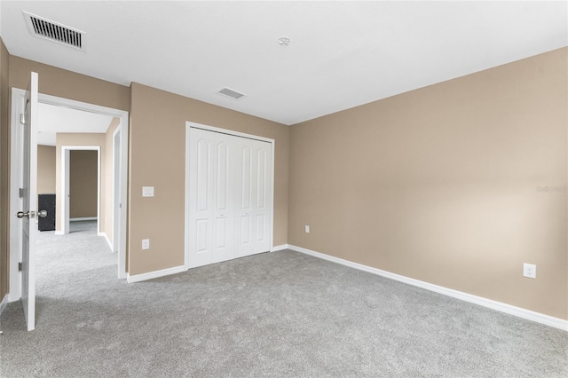 unfurnished bedroom with light colored carpet and a closet