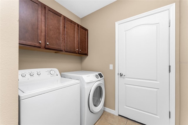 laundry room with cabinets, light tile patterned floors, and washing machine and clothes dryer