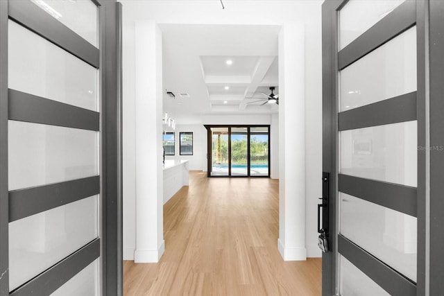 corridor with beamed ceiling, light wood-type flooring, and coffered ceiling