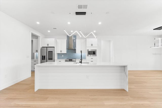 kitchen featuring sink, hanging light fixtures, wall chimney range hood, and appliances with stainless steel finishes