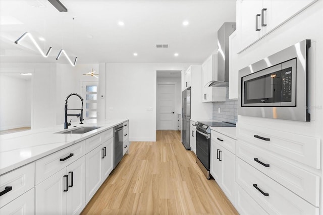 kitchen with sink, white cabinets, light hardwood / wood-style flooring, and appliances with stainless steel finishes