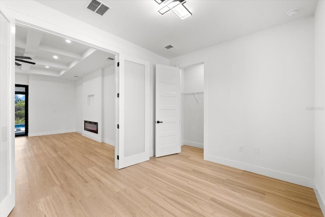 spare room featuring beamed ceiling, ceiling fan, and light hardwood / wood-style flooring