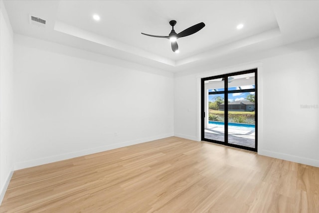 unfurnished room featuring a tray ceiling, light hardwood / wood-style flooring, and ceiling fan