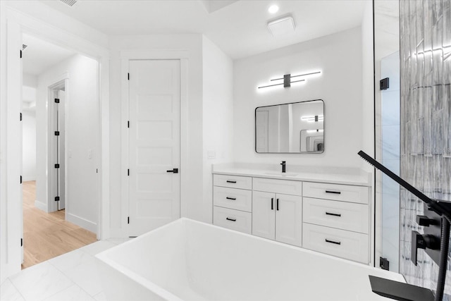 bathroom with a bathing tub, hardwood / wood-style floors, and vanity