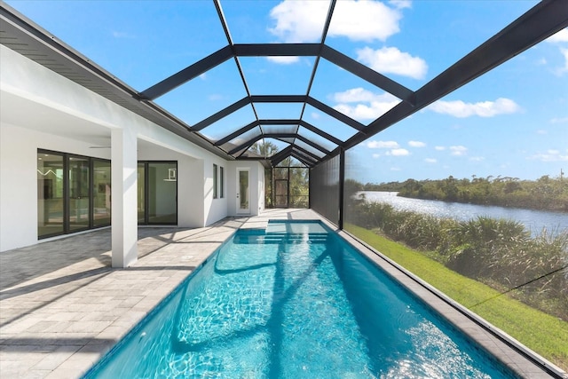 view of pool with a patio area, ceiling fan, a water view, and glass enclosure