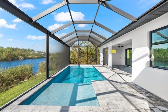 view of pool featuring a lanai, ceiling fan, a patio area, and a water view