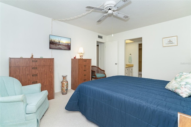 bedroom featuring a textured ceiling, ensuite bath, light carpet, and ceiling fan