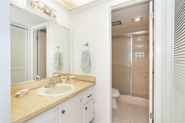 bathroom with tile patterned flooring, vanity, toilet, and a shower with shower door