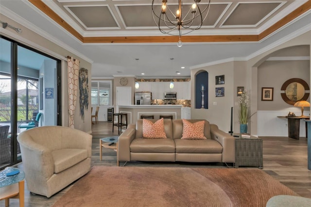 living room featuring hardwood / wood-style flooring, crown molding, and an inviting chandelier