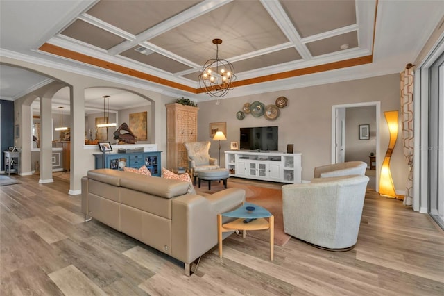 living room with an inviting chandelier, ornamental molding, coffered ceiling, and light wood-type flooring