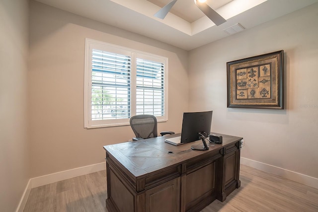 office area featuring light hardwood / wood-style floors, ceiling fan, and a tray ceiling