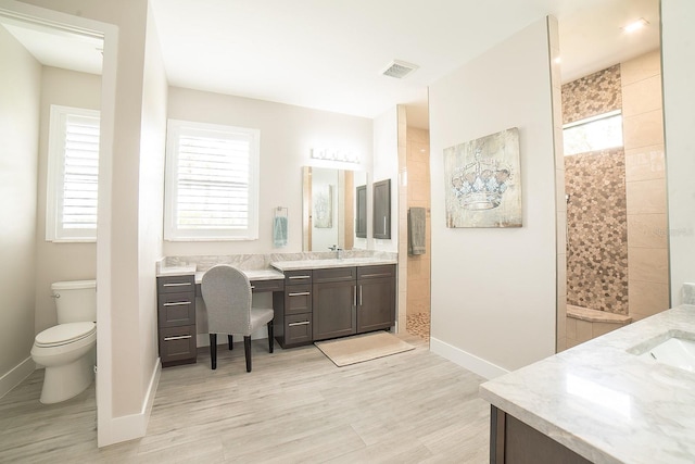 bathroom featuring tiled shower, hardwood / wood-style floors, vanity, and toilet