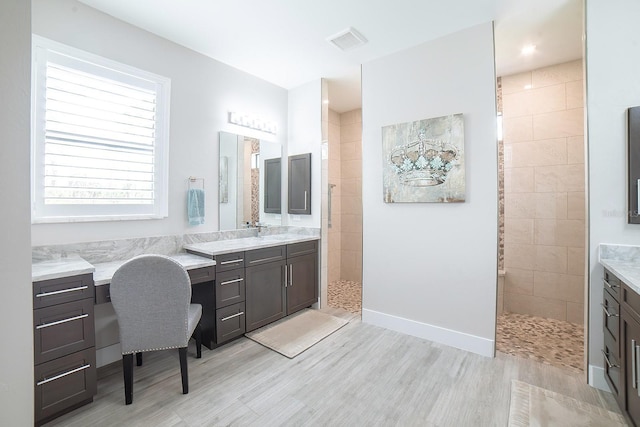 bathroom featuring tiled shower, hardwood / wood-style floors, and vanity