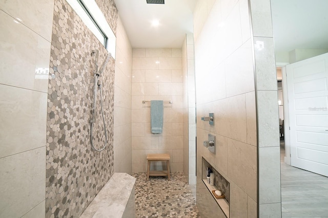 bathroom featuring walk in shower and tile walls