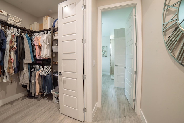 walk in closet with light hardwood / wood-style floors