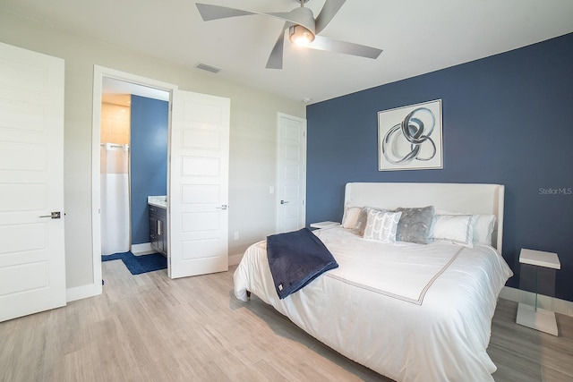 bedroom featuring light wood-type flooring, ensuite bathroom, and ceiling fan