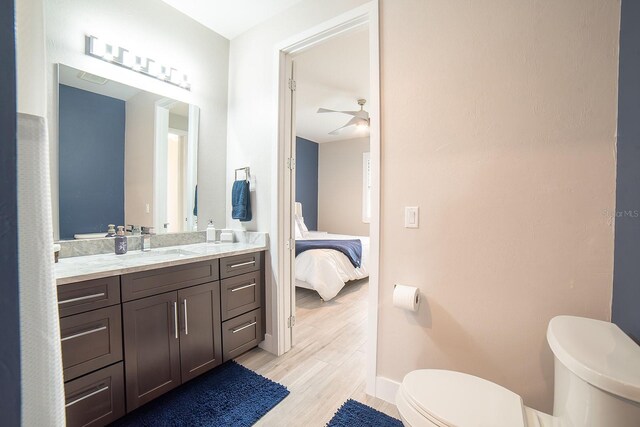 bathroom with ceiling fan, vanity, hardwood / wood-style flooring, and toilet