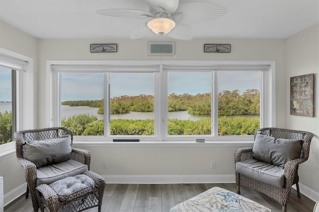 interior space with ceiling fan, a water view, and wood-type flooring