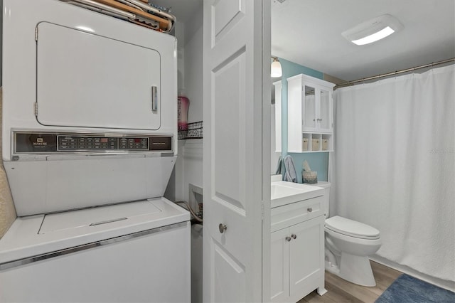 clothes washing area featuring stacked washer / dryer and light hardwood / wood-style flooring