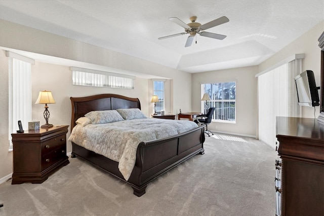 bedroom with light carpet, a raised ceiling, and ceiling fan