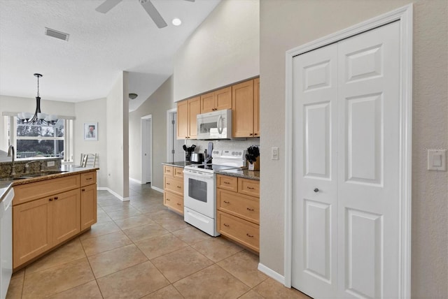 kitchen featuring light brown cabinetry, sink, hanging light fixtures, and white appliances