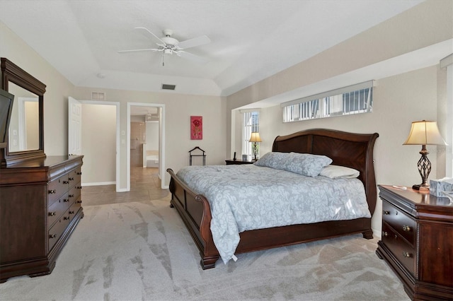 bedroom featuring light colored carpet, ensuite bath, ceiling fan, and a tray ceiling