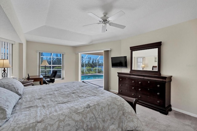 carpeted bedroom with access to outside, ceiling fan, a tray ceiling, and a textured ceiling