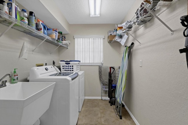 laundry room with sink, light tile patterned floors, a textured ceiling, and independent washer and dryer