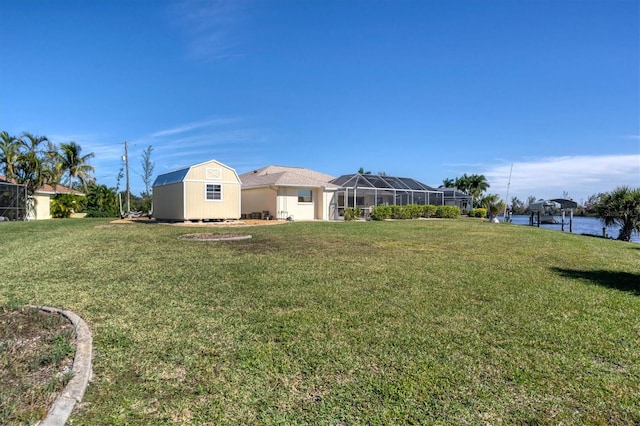 view of yard featuring a lanai, a water view, and a storage shed